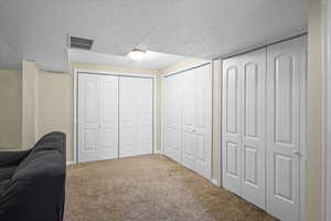 Carpeted bedroom featuring a textured ceiling and two closets