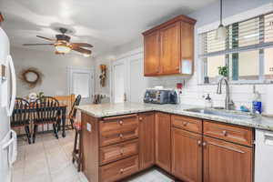 Kitchen featuring stainless steel dishwasher, sink, kitchen peninsula, hanging light fixtures, and backsplash