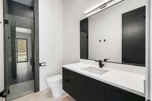 Bathroom with walk in shower, vanity, tile patterned flooring, and toilet