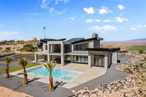 Back of property with a mountain view, a balcony, a swimming pool with hot tub, and a patio