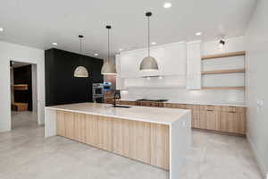 Kitchen with pendant lighting, sink, an island with sink, appliances with stainless steel finishes, and white cabinetry