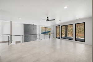 Tiled empty room featuring a textured ceiling and ceiling fan