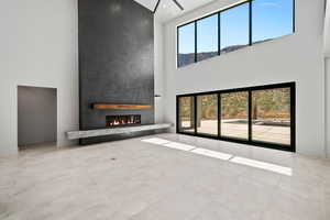 living room featuring a fireplace, a healthy amount of sunlight, a towering ceiling, and light tile patterned floors