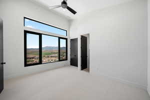 Unfurnished bedroom featuring light carpet, multiple windows, and a mountain view