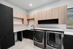 Washroom with cabinets, separate washer and dryer, and sink