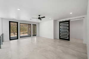 Spare room with ceiling fan and a barn door