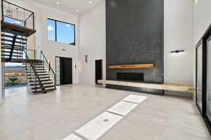 Living room featuring a fireplace and a high ceiling. Spinal Staircase