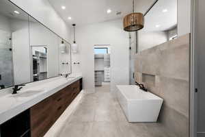 Bathroom with lofted ceiling, shower with separate bathtub, and vanity