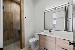 Bathroom featuring walk in shower, vanity, and toilet