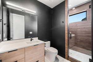 Bathroom featuring an enclosed shower, vanity, and toilet