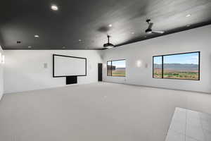 Carpeted cinema room with lofted ceiling, ceiling fan, and a textured ceiling