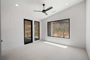 Carpeted empty room with ceiling fan and vaulted ceiling