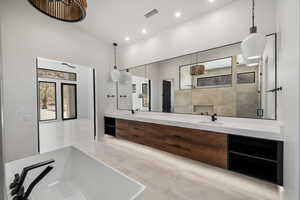 Bathroom with high vaulted ceiling, tile patterned flooring, separate shower and tub, and vanity