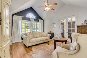 Living room with french doors, light wood-type flooring, vaulted ceiling, and ceiling fan