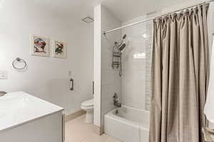 Full bathroom with vanity, shower / bath combo with shower curtain, toilet, and tile patterned floors