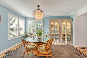 Dining room with crown molding, hardwood / wood-style floors, and a chandelier