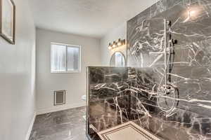 Bathroom with a tile shower, toilet, and a textured ceiling