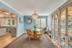 Dining room with an inviting chandelier, crown molding, light hardwood / wood-style floors, and a wealth of natural light