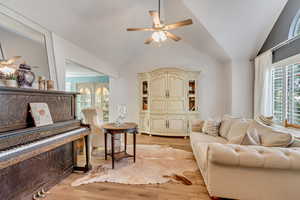 Living room featuring ceiling fan, lofted ceiling, and light wood-type flooring