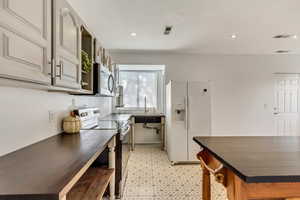 Kitchen featuring white fridge with ice dispenser, sink, and electric range oven