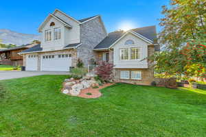 View of front of property with a mountain view, a garage, and a front lawn