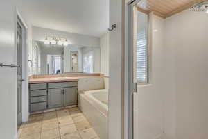 Bathroom featuring tiled tub, tile patterned flooring, and vanity