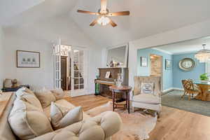 Living room featuring ceiling fan with notable chandelier, french doors, vaulted ceiling, and light hardwood / wood-style flooring