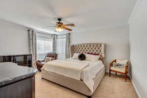 Carpeted bedroom featuring crown molding and ceiling fan