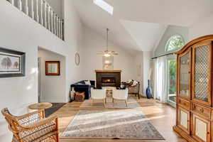 Interior space featuring a skylight, light wood-type flooring, high vaulted ceiling, and ceiling fan