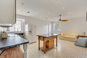 Kitchen with ceiling fan, plenty of natural light, a kitchen bar, and white refrigerator with ice dispenser