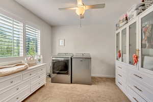 Clothes washing area with ceiling fan, light carpet, and independent washer and dryer