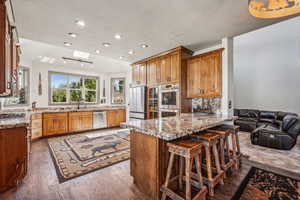 Kitchen featuring a skylight, decorative backsplash, appliances with stainless steel finishes, wood finished floors, and a peninsula