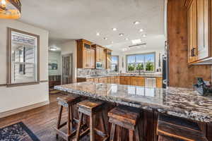 Kitchen with a breakfast bar area, stainless steel appliances, dark wood-type flooring, a peninsula, and backsplash