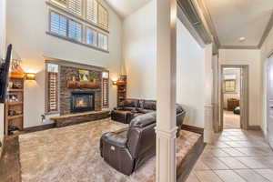 Living room with a fireplace, plenty of natural light, a towering ceiling, and light tile patterned floors