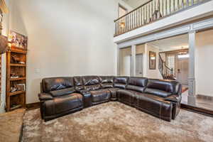 Living room with a high ceiling, visible vents, stairway, and ornate columns
