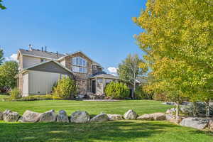 View of front facade with stone siding, a patio, crawl space, and a front yard