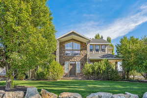 View of front of house with stone siding and a front yard