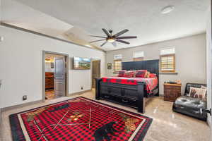 Bedroom featuring light speckled floor, a ceiling fan, a textured ceiling, ensuite bath, and baseboards