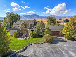 View of front of house with a mountain view, a garage, stone siding, driveway, and a front yard