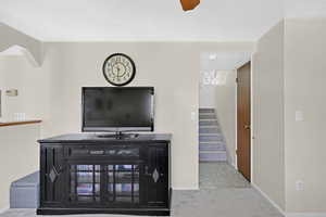 Carpeted living room with a textured ceiling and ceiling fan