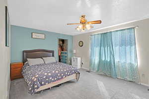 Carpeted bedroom featuring ceiling fan, a textured ceiling, a closet, and a spacious closet