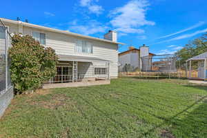 Rear view of house featuring a trampoline, a patio, and a yard