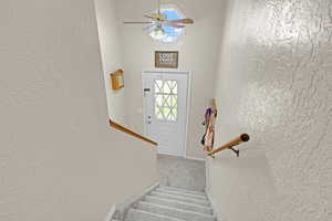 Stairs featuring ceiling fan and carpet floors