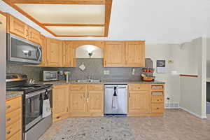 Kitchen featuring light brown cabinets, sink, a textured ceiling, backsplash, and stainless steel appliances