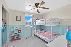 Carpeted bedroom with ceiling fan, a closet, and a textured ceiling