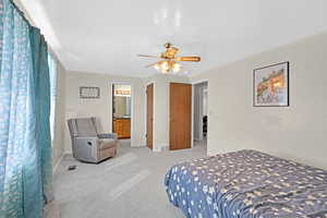 Carpeted bedroom featuring ceiling fan, a textured ceiling, and ensuite bath