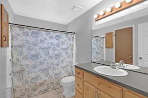 Bathroom with walk in shower, vanity, toilet, and a textured ceiling