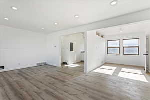 Empty room featuring electric panel and light hardwood / wood-style flooring