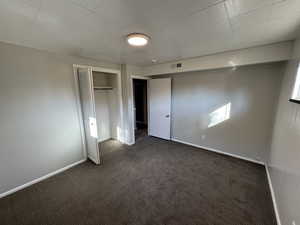 Unfurnished bedroom with dark carpet and a closet