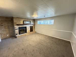 Unfurnished living room featuring a brick fireplace and carpet